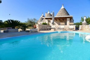 Piscina com edifícios de pedra ao fundo.