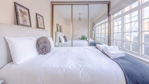 Una habitación de hotel moderna con una cama grande, una puerta corrediza que da a un balcón y cuadros en la pared.