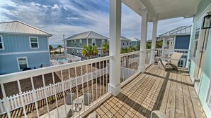 A covered porch with white railings, outdoor furniture, and a view of neighboring houses.