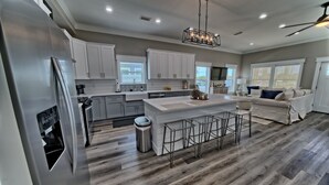 A modern kitchen with white cabinets, a stainless steel refrigerator, and a central island with bar stools.