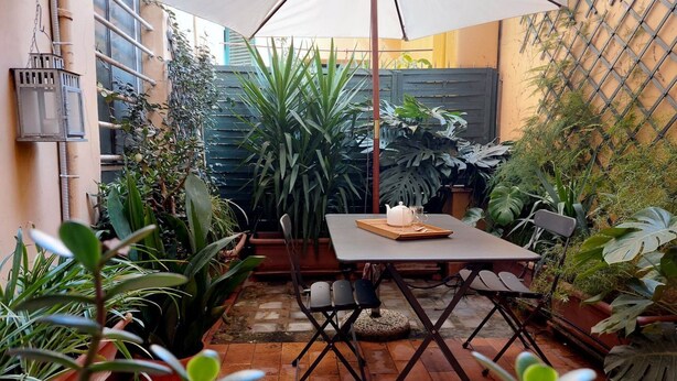 A patio area with a table and chairs, surrounded by potted plants and a large umbrella. - Laterano - Apartment for 4 pax with outdoor space close to the Coloseum (Roma)