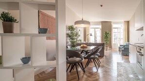 Une cuisine moderne avec un coin repas, un plancher en bois et une plante en pot.