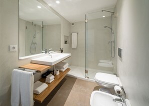 A modern bathroom with a glass-enclosed shower, a wooden vanity, and a white toilet. - Mouzinho 160 (Porto)