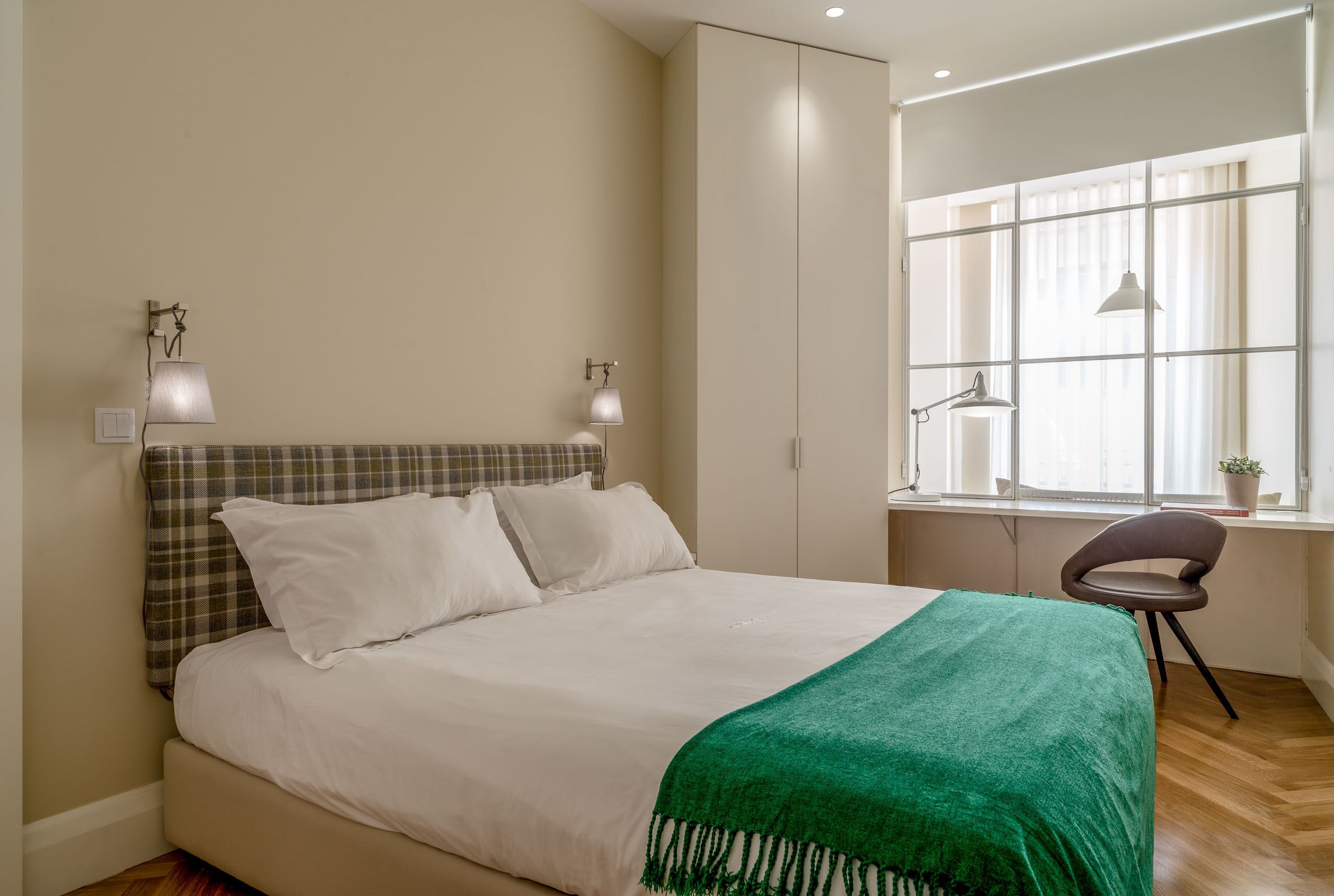 A bedroom with a bed, a desk, and a chair.
