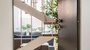 Un intérieur moderne avec un escalier menant à un espace de vie, une porte sombre et une plante en pot.