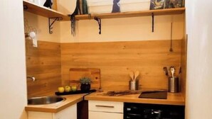 Una cocina compacta con muebles de madera, lavavajillas y una ventana sobre el fregadero.