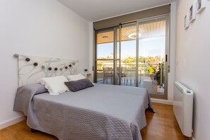 Une chambre avec un lit, un radiateur et une porte-fenêtre coulissante donnant sur un espace extérieur.