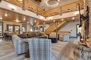 A spacious, multi-level interior with a central staircase, a cozy seating area with a sofa and chairs, and a dining area with a table and chairs.