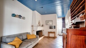 Uma sala de estar com um sofá cinza, um armário de madeira e uma lareira.