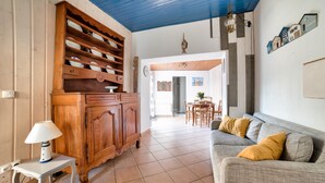 Uma sala de estar com um armário de madeira, um sofá cinza com almofadas amarelas e uma pequena mesa com um abajur.