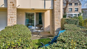 Ein zweistöckiges Haus mit Balkon, einer Terrasse und Gartenmöbeln sowie einem gepflegten Garten.
