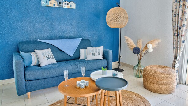 Ein blaues Wohnzimmer mit einer Couch, zwei Couchtischen und einer dekorativen Vase mit Pampasgras.