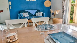 Ein Essbereich mit einem Tisch für zwei Personen, einer Schale mit Muscheln und einem blauen Teller.