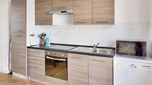Een moderne keuken met houten kastjes, een inbouwoven, een magnetron en een spoelbak.