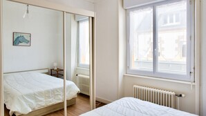 Een slaapkamer met twee bedden, een radiator, een raam en een spiegel.