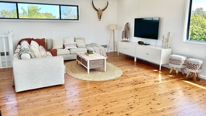 A modern living room with a sofa, coffee table, and TV. - The Ultimate Family Friendly Getaway (Long Jetty)