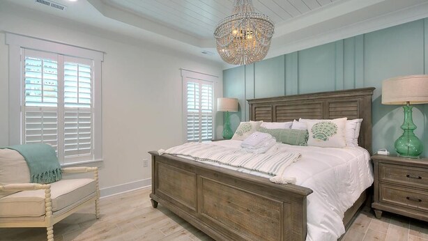 Una camera da letto con un letto di legno, un lampadario, una lampada verde e una sedia.