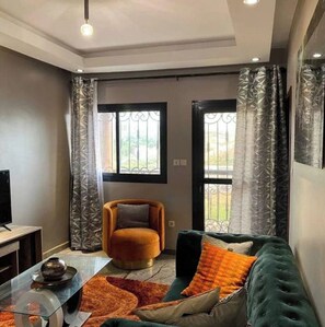 Relax in this stylish living room with a comfortable sofa, round ottoman, and flat-screen TV.