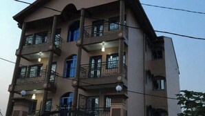 Un edificio de varios pisos con balcones, una entrada protegida por una reja y un accesorio de iluminación en cada balcón.