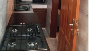 Cocina compacta con estufa a gas, microondas y pileta.