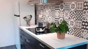 Une cuisine moderne avec des armoires noires, une hotte en acier inoxydable, un pare-feu décoratif et une plante en pot posée sur le comptoir.