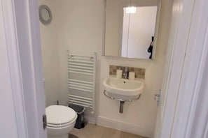 Un baño pequeño con inodoro, lavamanos y perchero para toallas.