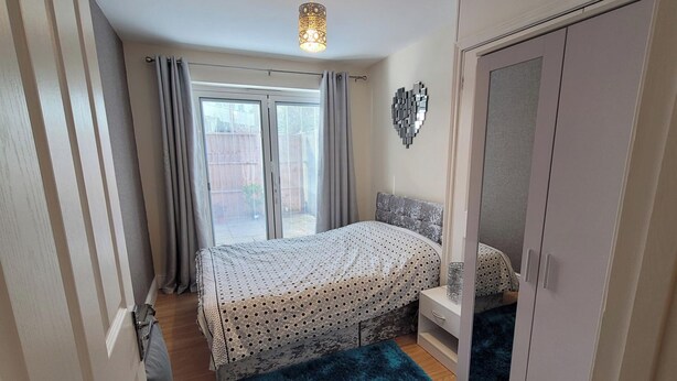 A bedroom with a bed, a wardrobe, a nightstand, and a window with curtains. - Apartment - Sleeps 2 - Parking - Wi-fi (Reading)