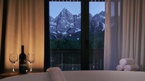 Ein Whirlpool mit Blick auf die Berge, eine Weinflasche und zwei Gläser auf einem Tisch.