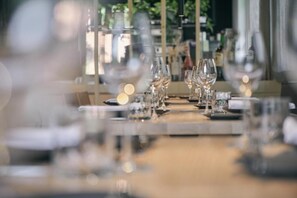 Un espace repas avec des tables dressées, de la verrerie impeccable et des chandeliers.