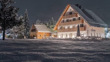 Ein großes, mehrgeschossiges Gebäude mit Satteldach, vermutlich ein Hotel oder Resort, umgeben von schneebedeckten Bäumen und einer verschneiten Landschaft.