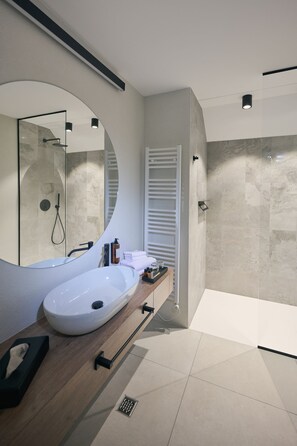 Une salle de bain moderne avec un grand lavabo ovale, un miroir, une douche et un porte-serviettes.
