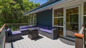 A covered deck with a sectional sofa and a small table, surrounded by glass doors and windows. - Mid Century Mountain Home on 3 acres - 10 Minutes to DGO - AC-Hot Tub-Views (Durango)