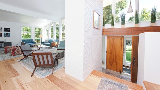 A spacious living room with a high ceiling, large windows, and a wooden staircase leading to an outdoor area. - Mid Century Mountain Home on 3 acres - 10 Minutes to DGO - AC-Hot Tub-Views (Durango)