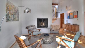 A modern living room with a fireplace, wooden furniture, and a staircase leading to an upper level. - Mid Century Mountain Home on 3 acres - 10 Minutes to DGO - AC-Hot Tub-Views (Durango)