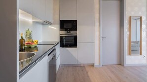 A modern kitchen with white cabinetry, a built-in oven, and a stainless steel countertop. - Luxurious Soft Flat | Balcony and Pool by HostWise (Vila Nova de Gaia)