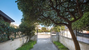 A concrete pathway flanked by low walls and a tree-lined path leading to a gate. - 3208 Complesso Pergolesi - Bilo PT by Barbarhouse (Melendugno)