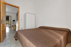 Ein Schlafzimmer mit einem Bett, einem Kleiderschrank und einer Tür zu einem anderen Raum.