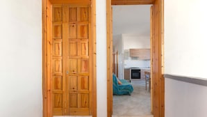 A hallway with wooden doors leading to a room with a bed and a television. - 3209 Complesso Pergolesi - Appartamento DX by Barbarhouse (Melendugno)