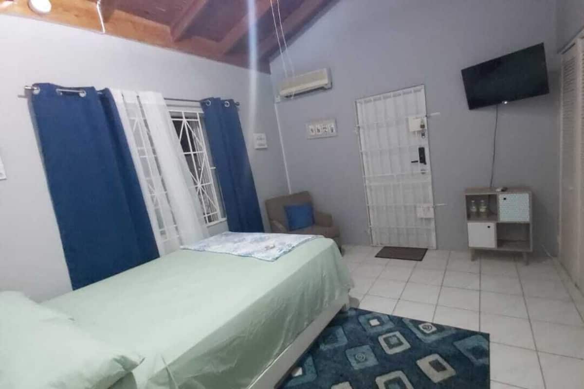 A bedroom with a bed, a TV, a wardrobe, and a small table.