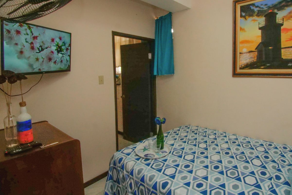 A room with a bed, a desk, a chair, a painting, and a window with curtains.