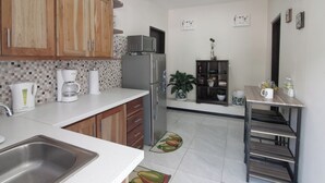 Een kleine keuken met houten kastjes, een roestvrijstalen koelkast, een koffiezetapparaat en een magnetron.