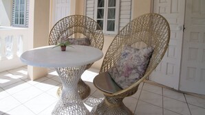 Een kamer met een ronde tafel en twee rieten stoelen met kussens.