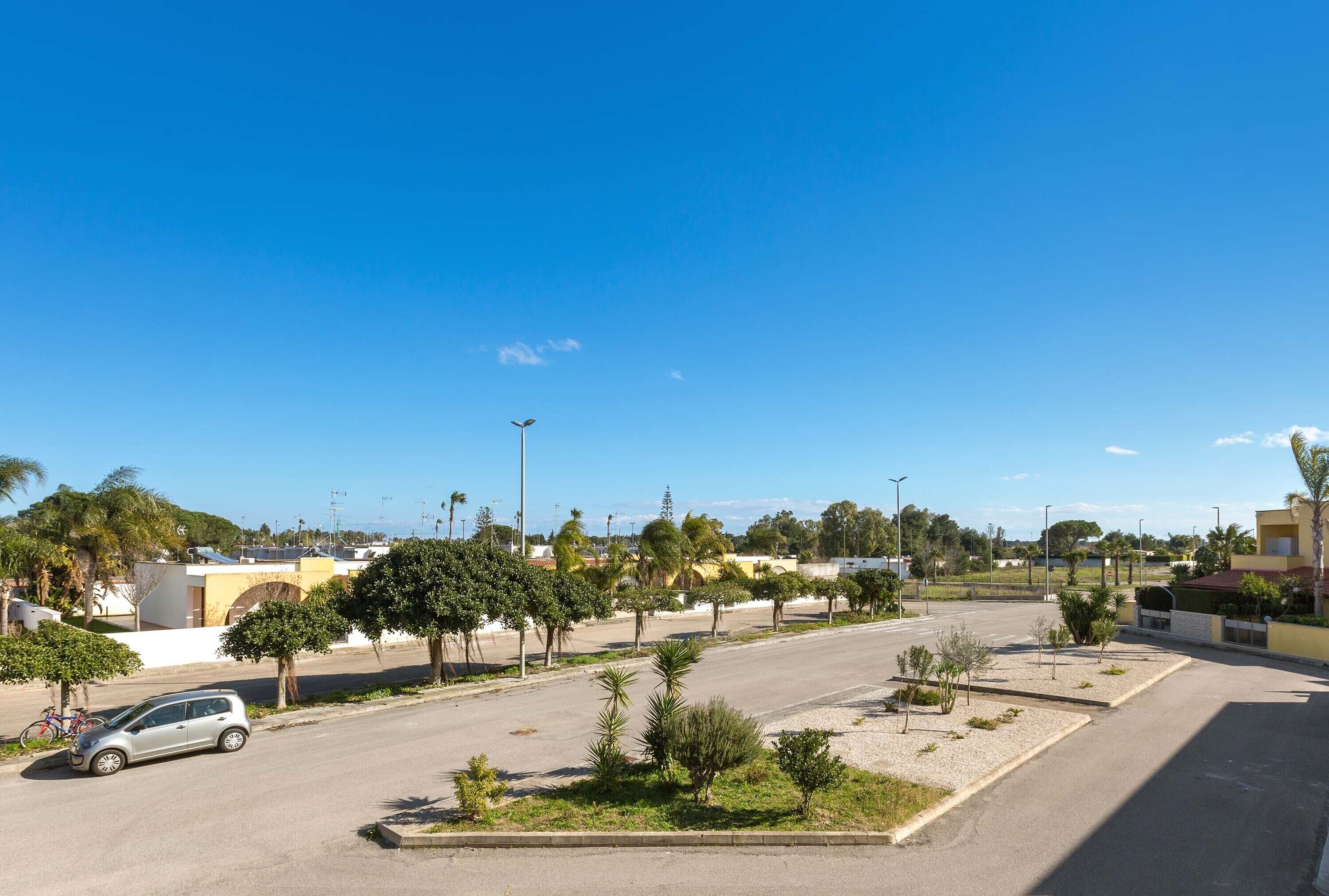A parking lot with a car, trees, and buildings in the background.