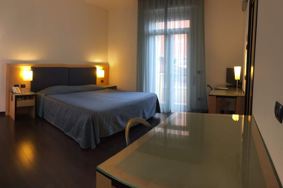 Une chambre d’hôtel avec un lit, des tables de chevet, un bureau et une chaise.