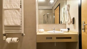 Un bagno con lavandino, specchio, porta asciugamani e carta igienica.