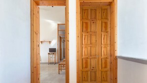 A hallway with wooden doors, a small table with a chair, and a television on a stand.
