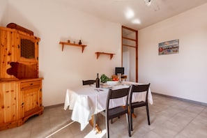 A dining area with a wooden cabinet, a table set for two, and a television on a stand. - 3210 Complesso Pergolesi - Appartamento SN by Barbarhouse (Melendugno)