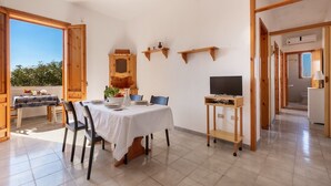 A dining area with a table set for four, a television on a stand, and a view of the outdoors.