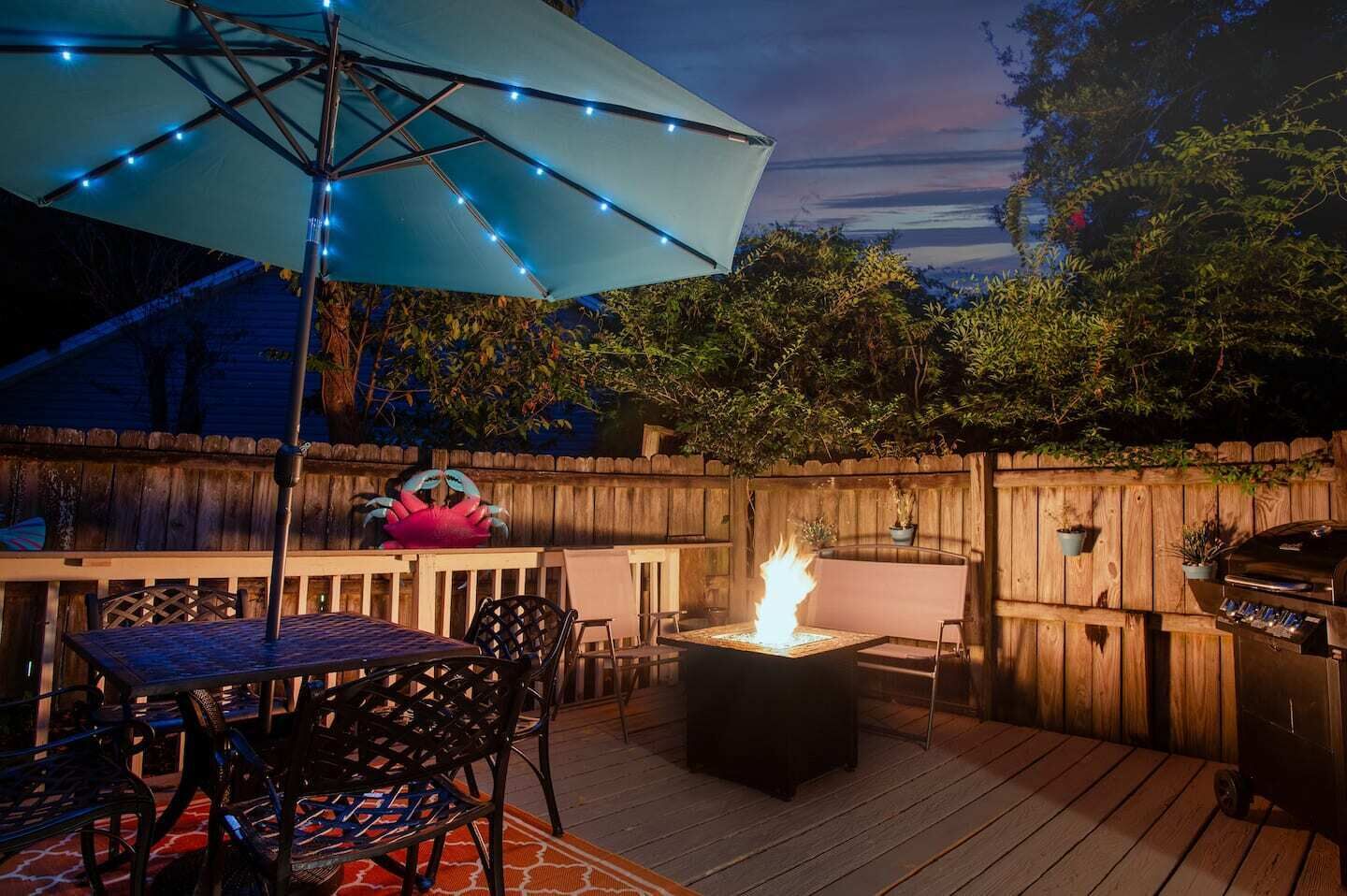 Una terraza al aire libre con una chimenea, una mesa y sillas, y una parrilla.