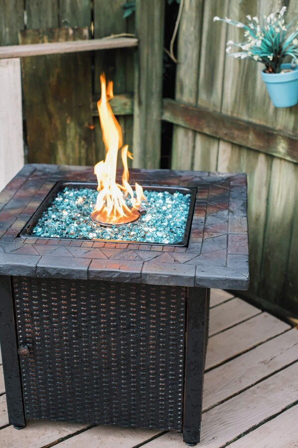 A square outdoor fire feature with a textured black base and a glass top.